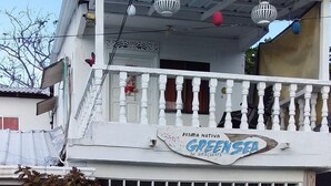 Un edificio de dos pisos con un balcón, un letrero que dice "POSADA NATIVA GREENSEA" y una entrada con reja.