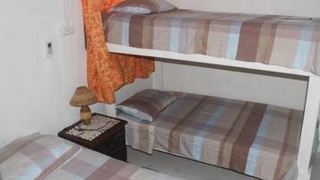 A bunk bed room with two beds, a nightstand with a lamp, and a patterned curtain.