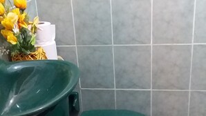 A small bathroom with a green toilet, a green sink, and a floral rug on the floor. - Room-green Sea Inn San Luis (San Andrés)