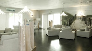 A modern hotel lobby with a seating area, a reception desk, and a large window. - Beautiful apartment in villa for 4 guests with pool, hot tub, TV, terrace and pets allowed (Château-d'olonne)