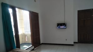 A bedroom with a bed, a TV mounted on the wall, and a sliding door leading to a balcony. - D Kir's Homestay (Depok)