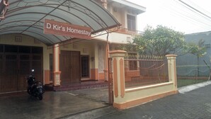 A hotel entrance with a covered porch, a sign reading "D Kir's Homestay," and a motorcycle parked in front. - D Kir's Homestay (Depok)