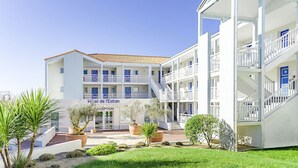 Un hôtel comprenant plusieurs étages, un espace de réception et un jardin bien entretenu.