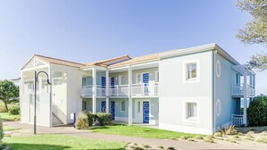 Un bâtiment à deux étages, doté d’un toit plat, de plusieurs balcons et d’une pelouse bien entretenue.