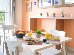 Una mesa de desayuno con cruasanes, jugo de naranja y un periódico.