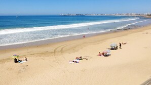 A beach with people sunbathing and swimming, a sailboat in the distance, and a city skyline in the background. - Cosy apartment for 5 guests with WIFI, pool, TV, terrace and pets allowed (Château-d'olonne)