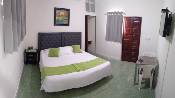 A neatly arranged bedroom with a bed, bedside table, and a small desk with a chair. - Hostal Arboleda, Colonial Zone, Santo Domingo (Santo Domingo)