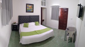 Ein ordentlich eingerichtetes Schlafzimmer mit Bett, Nachttisch und kleinem Schreibtisch mit Stuhl.
