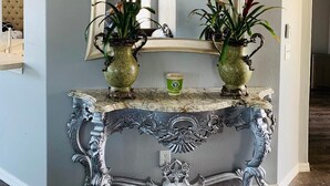 A hallway with a large mirror, two ornate vases with plants, and a decorative console table. - Near Img And Siesta Key Beach Paradise Home (Bradenton)