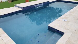 A rectangular swimming pool with a tiled edge and a small waterfall feature. - Near Img And Siesta Key Beach Paradise Home (Bradenton)