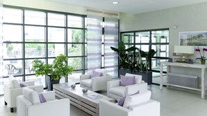 Ein modernes Wohnzimmer mit weißen Sofas, einem Couchtisch und großen Fenstern mit Blick ins Freie.