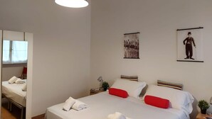 A hotel room with a large bed, a bedside table, a mirror, and artwork on the walls. - Bnbook-Ughelli Rho Studio (Rho)