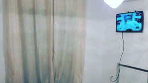 Une chambre à coucher avec un lit, un téléviseur fixé au mur et un radiateur.