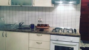 Ett kök med vita skåp, en bänkskiva i granit, en inbyggd mikrovågsugn, en spis och en kaffebryggare.