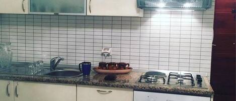 A kitchen with white cabinets, a granite countertop, a built-in microwave, a stove, and a coffee maker.