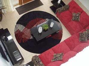 A modern living room with a black coffee table, red sofas, patterned cushions, and a black rug.
