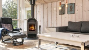 A cozy room with a fireplace, a leather chair, a sofa, and a table. - 6 Person Holiday Home in Hemmet-by Traum (Hemmet)