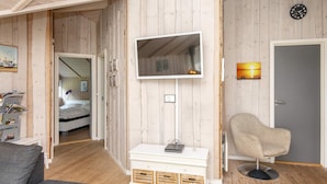A room with a wooden interior, a flat-screen TV mounted on the wall, a chair, and a bed in the background. - 6 Person Holiday Home in Hemmet-by Traum (Hemmet)