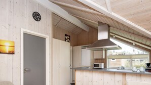 A modern kitchen with wooden cabinetry, a built-in microwave, and a window overlooking the garden. - 6 Person Holiday Home in Hemmet-by Traum (Hemmet)