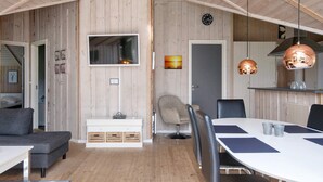 A modern interior with a dining area, a sofa, a TV mounted on the wall, and a wooden ceiling. - 6 Person Holiday Home in Hemmet-by Traum (Hemmet)