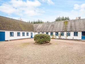 A traditional building with a gravel courtyard, white walls, and blue doors. - 14 Person Holiday Home in Orsted (Ørsted)