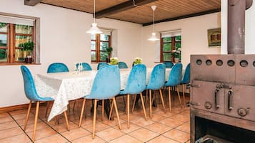 A dining area with a wooden table, blue chairs, and a rustic stove.