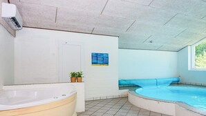 Een wellnessruimte met een whirlpool, een zithoek en een raam.