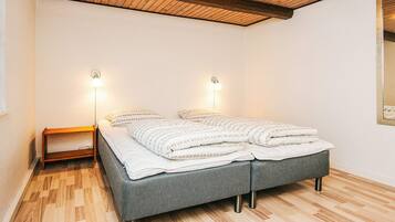 Una camera da letto con un letto, lampade da comodino, un tavolino e un soffitto in legno.