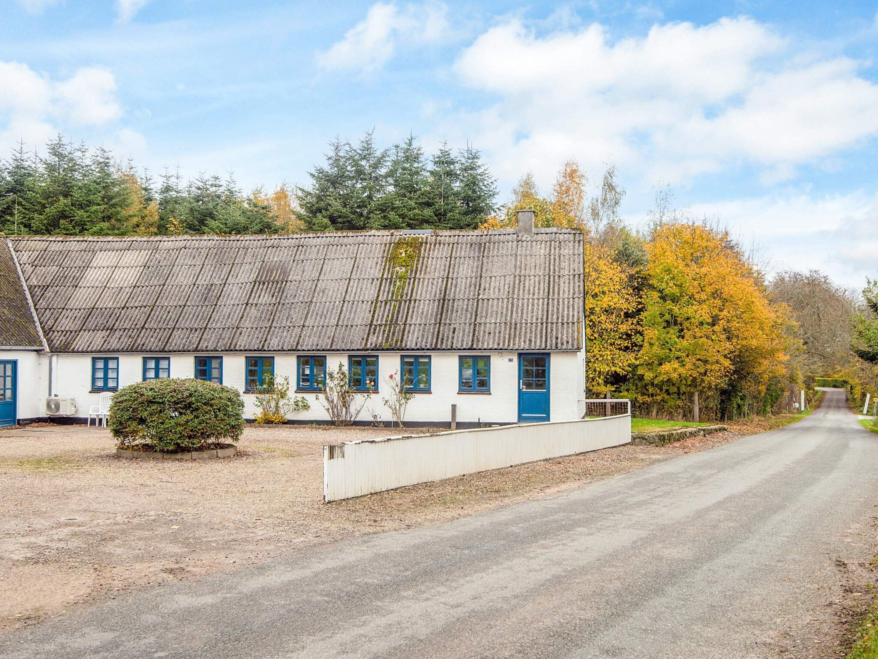 Valkoinen rakennus, jossa on siniset koristeet ja harmaa katto, sijaitsee sorapäällysteisen ajotien vieressä.