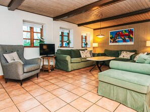 A living room with a television, green sofas, a wooden coffee table, and a painting on the wall. - 14 Person Holiday Home in Orsted (Ørsted)