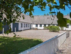 A building with a gravel courtyard, a wooden fence, and a small table. - 14 Person Holiday Home in Orsted (Ørsted)
