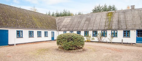 A traditional building with a gravel courtyard, white walls, and blue doors.