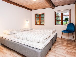Un dormitorio con cama, dos ventanas, una silla y una lámpara.