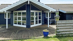 A house with a large bay window, a wooden deck, and a blue planter. - 5 Star Holiday Home in Rodby (Rodby)