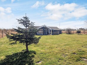 A house with a large lawn and a single tree in the foreground. - 5 Star Holiday Home in Rodby (Rodby)