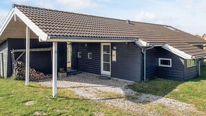 A modern house with a dark exterior, a tiled roof, and a covered porch. - 5 Star Holiday Home in Rodby (Rodby)