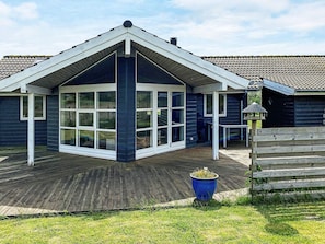 A house with a large bay window, a wooden deck, and a blue planter. - 5 Star Holiday Home in Rodby (Rodby)