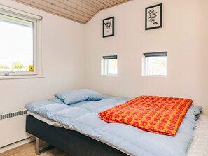 A bedroom with a bed, two windows, and artwork on the wall. - 5 Star Holiday Home in Rodby (Rodby)