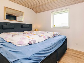 A bedroom with a bed, a headboard, a window, and a mirror. - 5 Star Holiday Home in Rodby (Rodby)