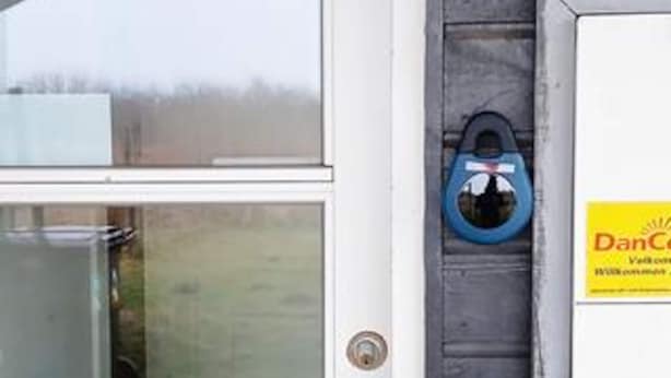 A door with a keyhole, a blue object hanging on the door, and a yellow sign with text. - 5 Star Holiday Home in Rodby (Rodby)