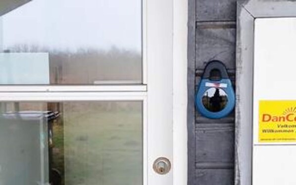 A door with a keyhole, a blue object hanging on the door, and a yellow sign with text.