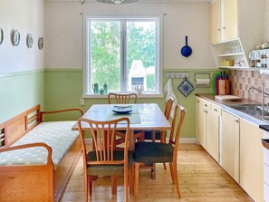 A kitchen with a dining table, wooden chairs, a window with a view of greenery, and a sink. - 6 Person Holiday Home in Overum (Overum)
