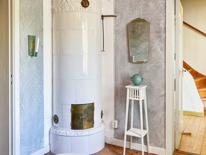 A corner room with a white cylindrical heater, a small white stool, and a mirror on the wall. - 6 Person Holiday Home in Overum (Overum)