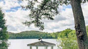 Un belvédère au bord d’un lac, avec une colline boisée en arrière-plan.