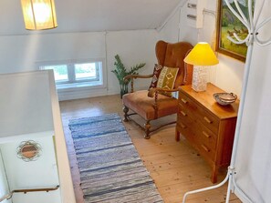 A cozy room with a wooden chair, a wooden dresser, a lamp, and a painting on the wall. - 6 Person Holiday Home in Overum (Overum)