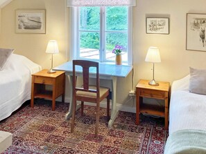 A room with two single beds, a wooden desk with a chair, a window with a view of greenery, and a patterned carpet. - 6 Person Holiday Home in Overum (Overum)