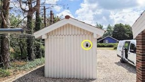 A small, single-story shed with a sloped roof, a circular window, and a door. - 4 Star Holiday Home in Orsted (Ørsted)