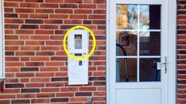 A brick wall with a white door and a utility meter mounted on it. - 4 Star Holiday Home in Orsted (Ørsted)