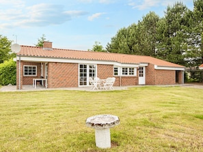 A brick house with a tiled roof, a patio with outdoor furniture, and a birdbath in the yard. - 4 Star Holiday Home in Orsted (Ørsted)