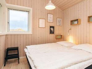 A bedroom with a bed, a window, a small table, and wall-mounted light fixtures. - 5 Star Holiday Home in Faaborg (Faaborg)